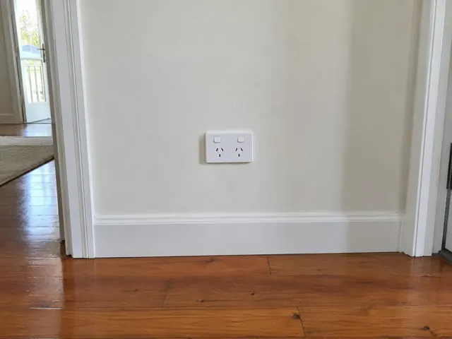 Double power point on a plain wall above timber floorboards in a hallway in Mudgeeraba